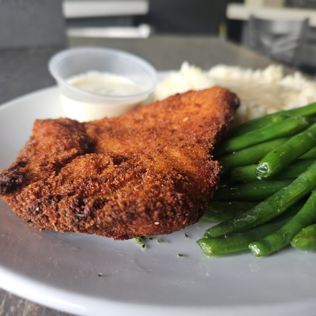 Mustard Crusted Chicken: Chicken breast coated in Dijon mustard, sour cream & our house made seasoned breadcrumbs, with a side stone ground mustard sauce, mashed potatoes, gravy, and fresh vegetables.