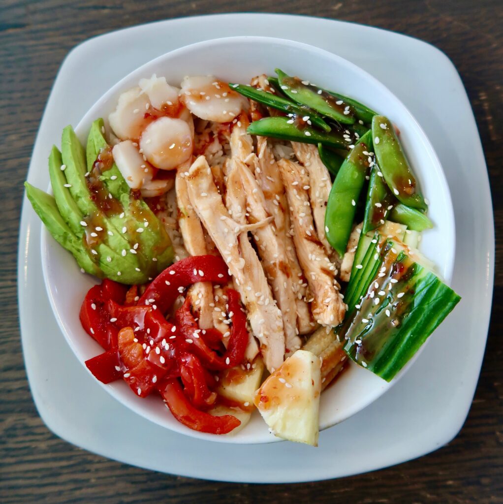 City Rice Bowl: Grilled shrimp or grilled chicken breast tossed in sweet Thai chili sauce over Jasmin rice, beautifully presented with julienne cucumber, snap peas, baby corn, grilled pineapple, avocado, roasted red peppers & water chestnuts finished with sesame seeds with a sweet Thai chili drizzle.