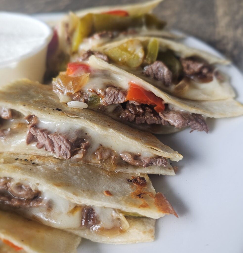 Quesadillas: Flour tortillas filled with your choice of chicken or steak,  cheddar & jack cheese, marinated onions & roasted peppers. Served with Jasmine rice, Pico de Gallo & sour cream