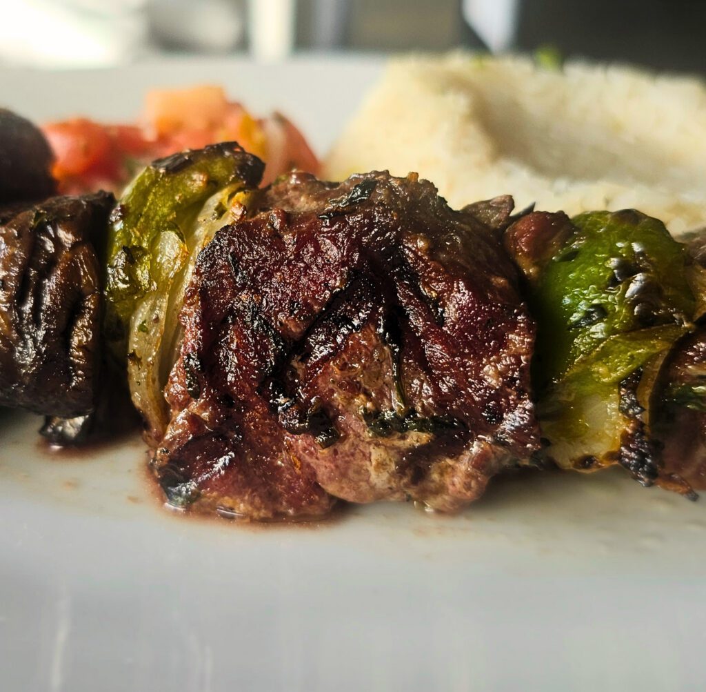 Marinated Sirloin Skewers: Marinated beef skewers with peppers, onion & mushrooms, with our chimichurri marinade, grilled on an open flame, served over a bed of rice and Pico de Gallo.