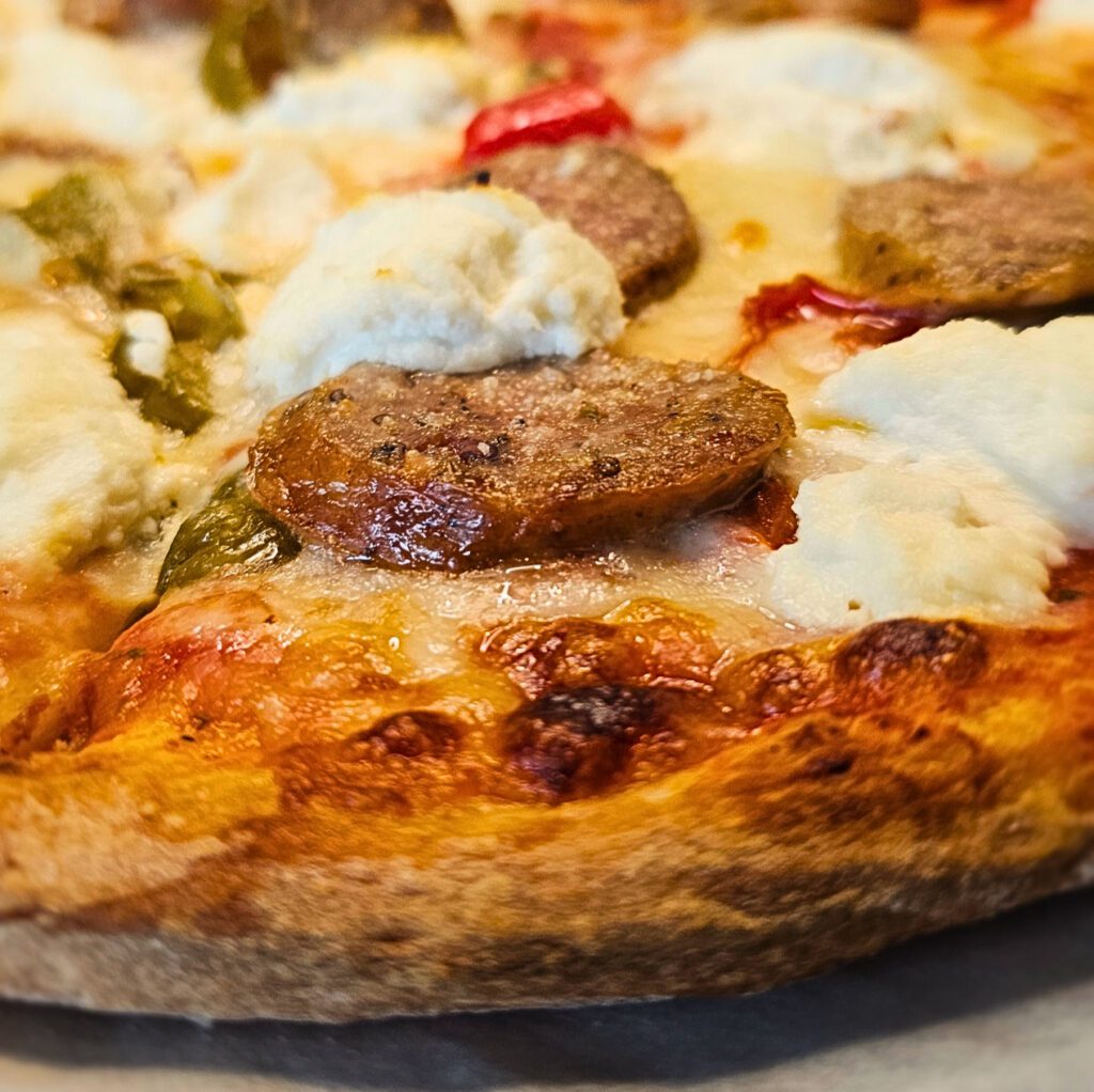 Sweet Italian Sausage & Ricotta Pizza: Hand stretched pizza dough topped with handmade tomato basil pizza sauce, sweet Italian sausage, roasted peppers & dollops of creamy ricotta cheese. Sprinkled with grated parmesan & mozzarella cheese.