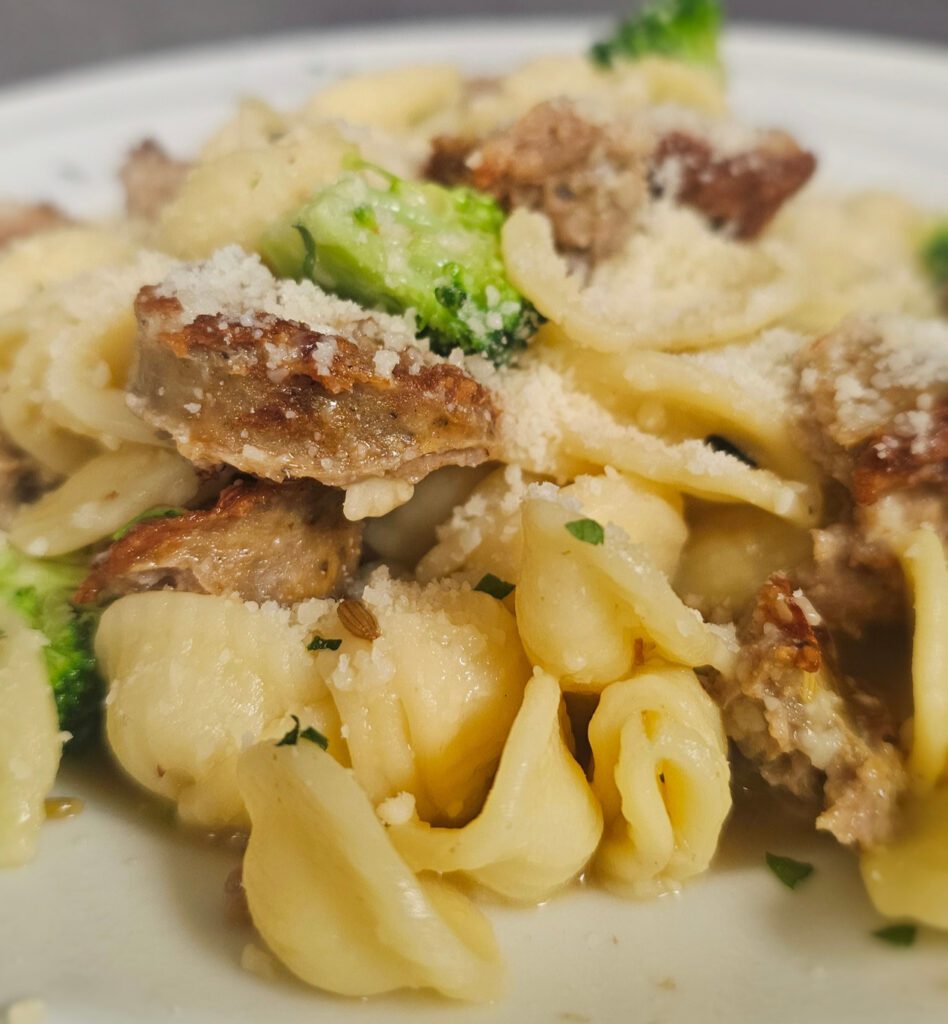 Orrecchiette w/Sausage & Broccoli: A rustic, savory pasta featuring ear-shaped semolina noodles tossed with crumbled sausage, tender-broccoli crowns, crisp kale, garlic, and shaved parmesan cheese in an EVOO, parmesan, wine sauce.