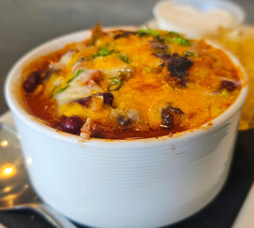 Chili: Perfectly seasoned ground beef loaded with peppers, onions, tomatoes, red kidney & black beans; topped with cheddar & jack cheese, sour cream, & scallions. with tortilla chips.