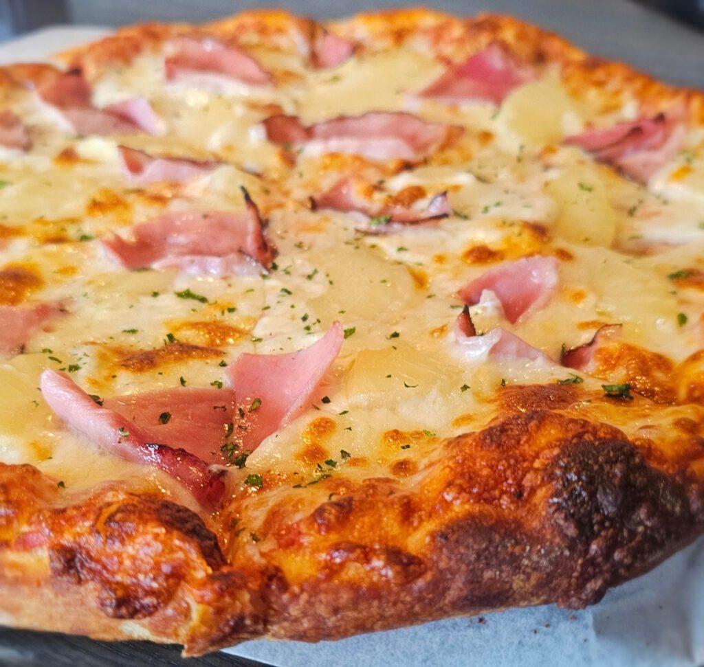 Hawaiian: Thin crust pizza with our handmade tomato basil pizza sauce, mozzarella & parmesan cheeses, topped with black forest ham and juicy pineapple, garnished with chopped parsley. (pineapple on a pizza?!? let debate start!)